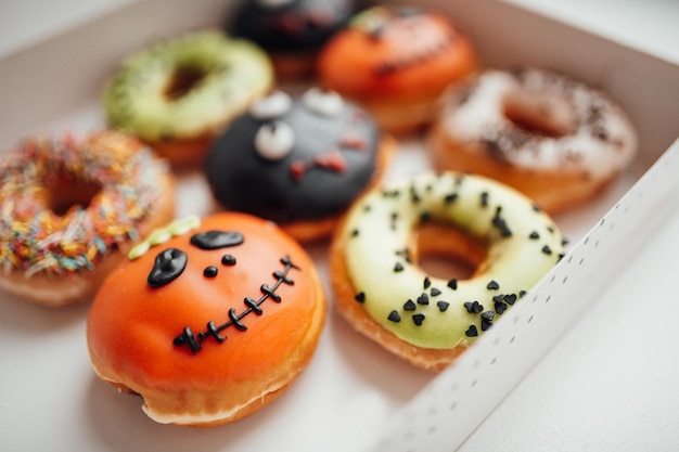 Assortment of halloween monsters with funny faces donuts in box at home interior