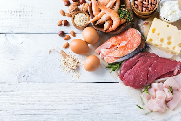 Assortment of healthy protein source and body building food Meat beef salmon chicken eggs dairy products milk cheese yogurt beans quinoa nuts oat meal Copy space background top view flat lay