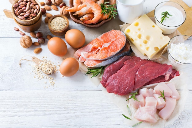 Assortment of healthy protein source and body building food Meat beef salmon shrimp chicken eggs dairy products milk cheese yogurt beans quinoa nuts oat meal Copy space background