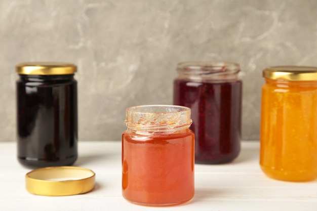 Assortment of jams, seasonal fresh berries and fruits on white background. Top view