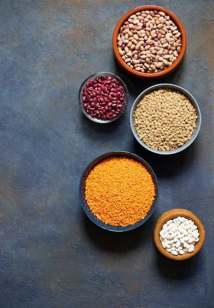 Assortment of legumes: beans and lentils. Raw healthy food. Vegetable protein. Dark background. Top view. Space for text