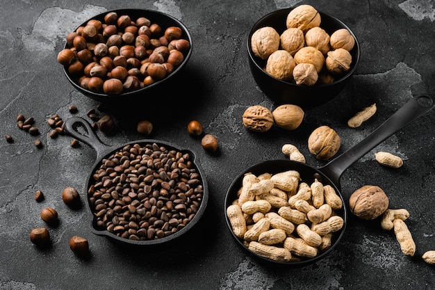 Assortment of nuts in shells peanut walnut pine nuts and hazelnut set on black dark stone table background