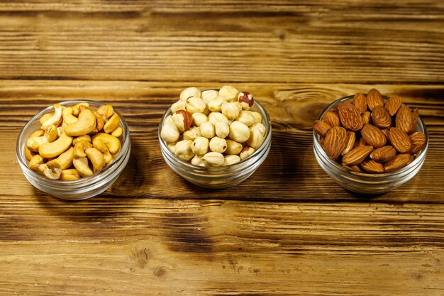 Assortment of nuts on wooden table Almond hazelnut and cashew in glass bowls Healthy eating concept