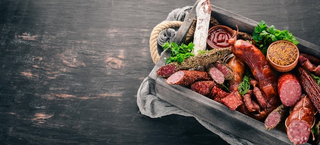 Assortment of sausages and snacks in a wooden box Sausage Fuet salami paperoni On a black background Top view Free space for your text