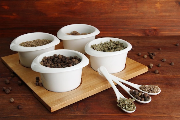 Assortment of spices in white spoons and bowls on wooden background