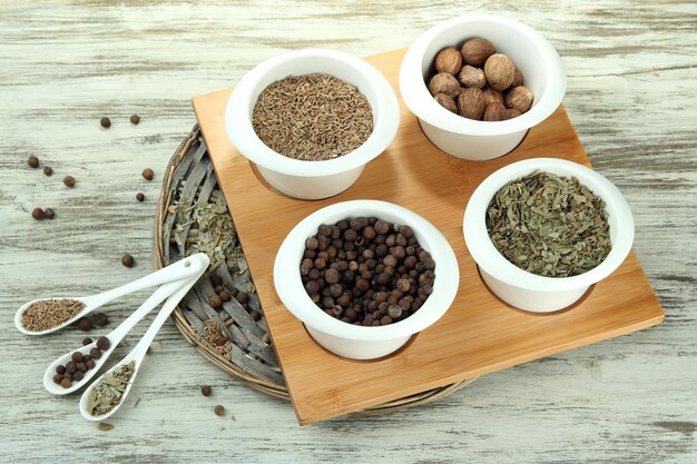 Photo assortment of spices in white spoons and bowls on wooden background