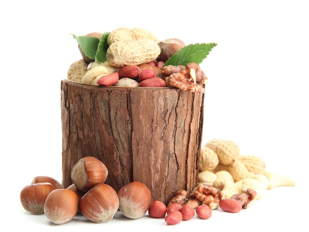 Assortment of tasty nuts with leaves in wooden vase isolated on white