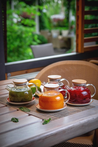 An assortment of teas in glass teapots on the summer terrace of the restaurant Ginger sea buckthorn and fruit tea