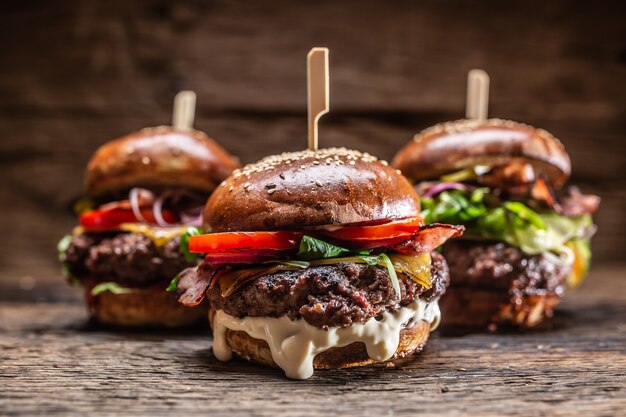 Assortment of three various burgers ready to be plated, with a dark wooden background.