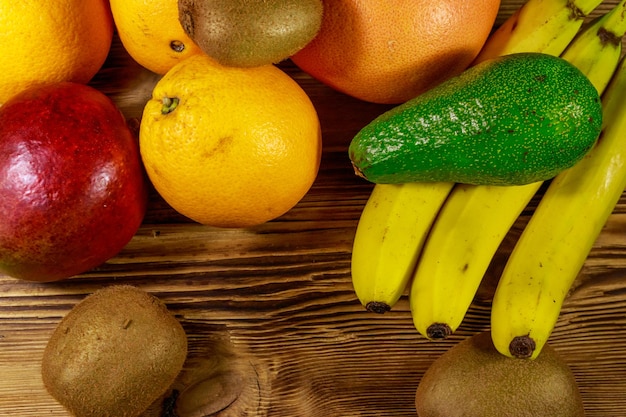 Assortment of tropical fruits on wooden table Still life with bananas mango oranges avocado grapefruit and kiwi fruits Top view