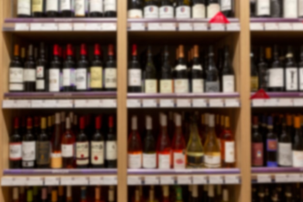 An assortment of wines on a showcase in a store. Lots of different alcohol on wooden shelves. Blurred.