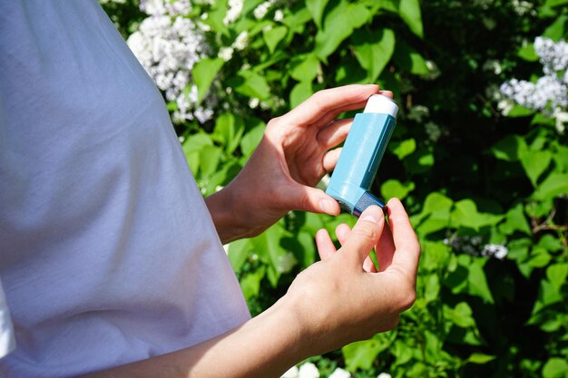 Asthmatic woman using inhaler from an asthma attack outdoor closeup