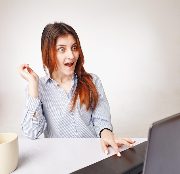 Astonished young woman working with computer