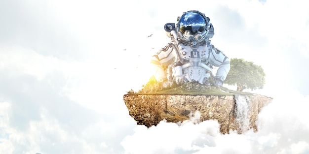 Astronaut against cloudy sky background and green tree. Mixed media