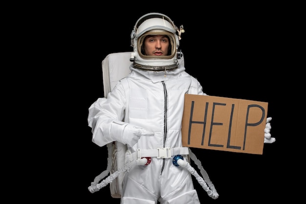 Astronaut day spaceman in cosmos space suit helmet holding HELP sign written on cupboard afraid