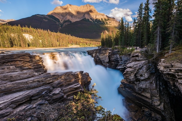 Athabasca Falls with mountain in the background that is yellow from the setting sun