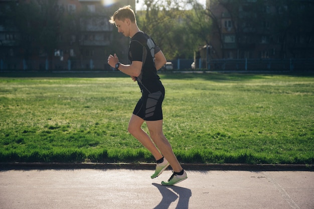 The athlete jogs in headphones on the lawn