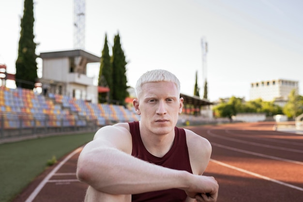 Athlete man relaxation pose sitting on running track