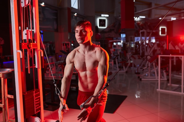 Athlete muscular bodybuilder training on simulator in the gym