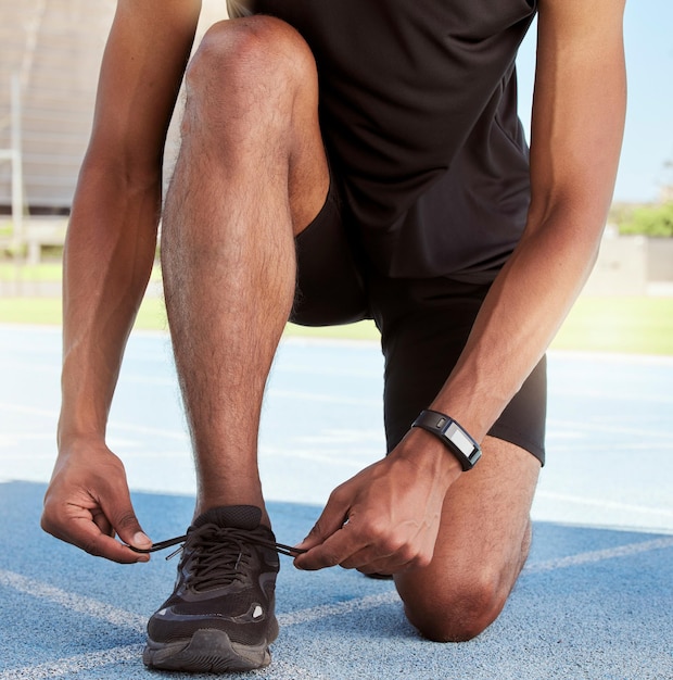 Athlete preparing for a race on the track Closeup of an athlete fastening his sneakers to prevent tripping while getting ready for cardio training and a workout on a running track