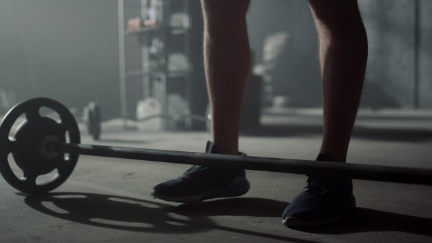 Athlete preparing sports equipment for exercise Man putting plates on barbell