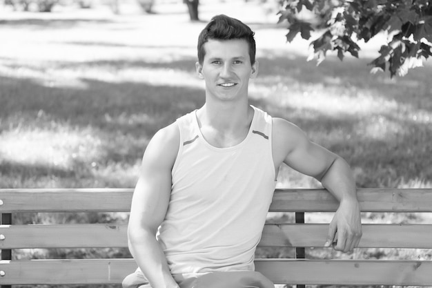 Athlete smiling on wooden bench in park