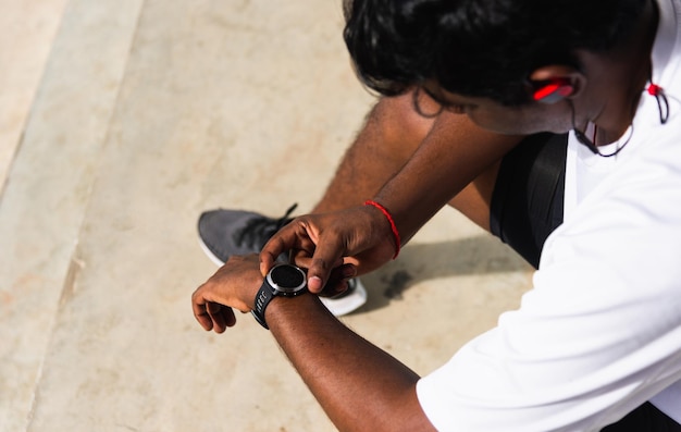 Athlete sport runner black man wear modern time smart watch he sitting resting before training run