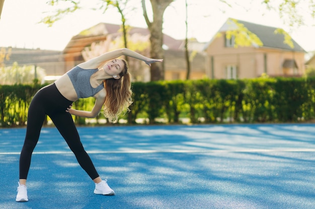 Athlete standing outdoors in the stadium and doing warmup on a sunny day