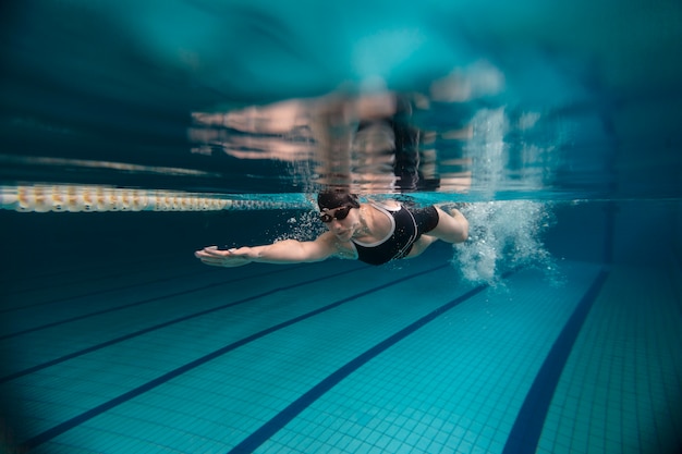 Athlete with goggles swimming underwater full shot