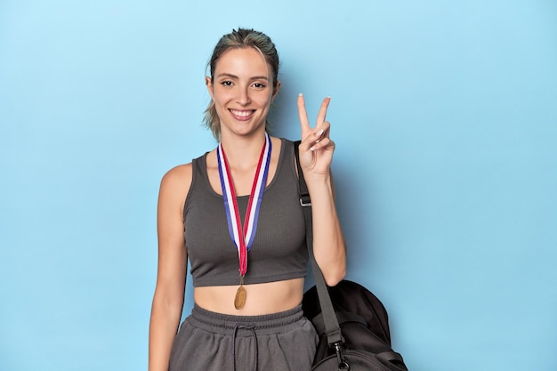 Athlete with medal and sports backpack showing number two with fingers