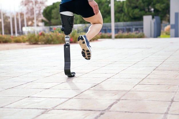 An athlete with a prosthetic leg is captured midstretch on a sunlit path