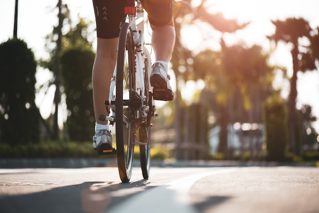 Athlete woman cyclist legs riding Mountain Bike on the road in the morning.