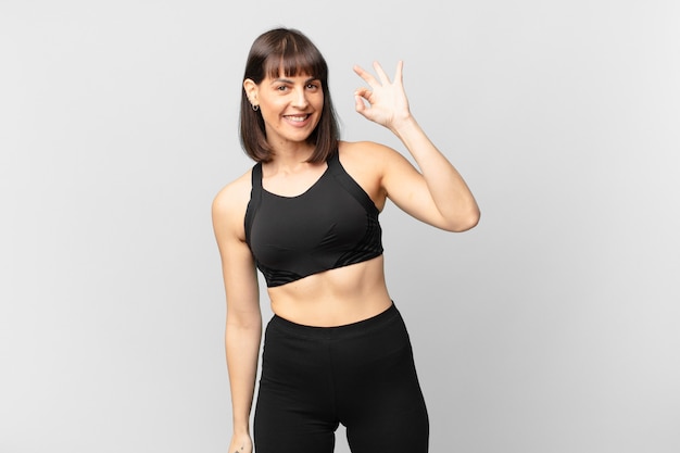 Athlete woman feeling happy, relaxed and satisfied, showing approval with okay gesture, smiling