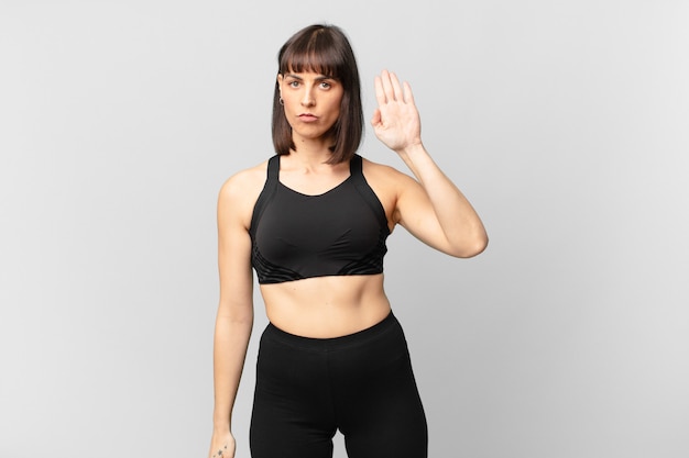 athlete woman looking serious, stern, displeased and angry showing open palm making stop gesture