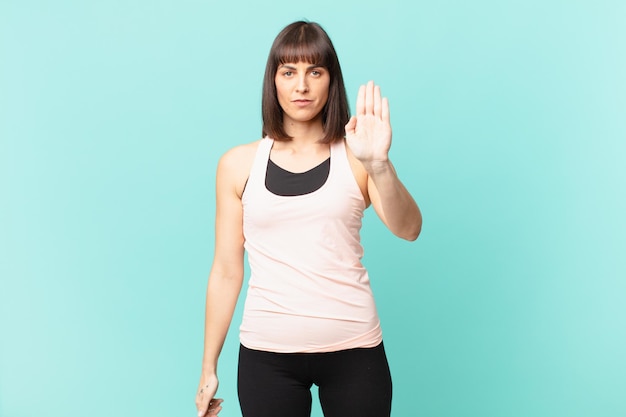 Athlete woman looking serious, stern, displeased and angry showing open palm making stop gesture