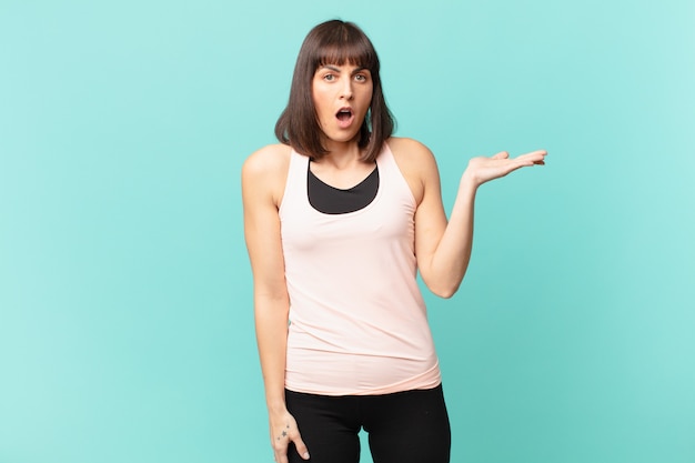 Athlete woman looking surprised and shocked, with jaw dropped displaying with an open hand on the side