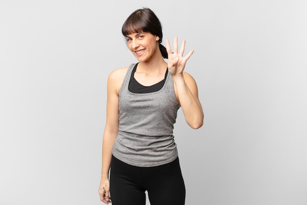 Athlete woman smiling and looking friendly, showing number four or fourth with hand forward, counting down