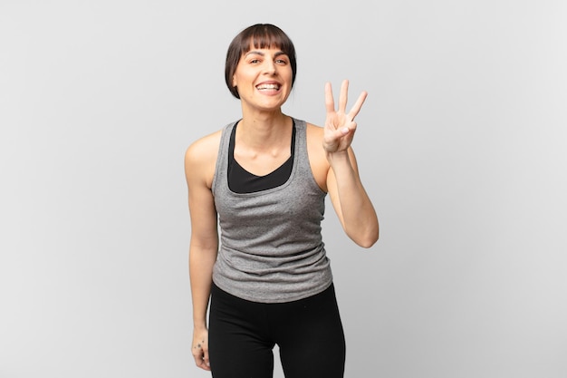 athlete woman smiling and looking friendly, showing number three or third with hand forward, counting down