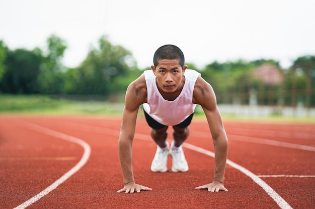 Athletes sport man runner wearing white sportswear to push up stretching and warm up before practicing on a running track at a stadium Athlete sportman prepare to training for competition race