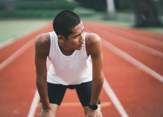 Athletes sport man runner wearing white sportswear tired wipe sweat and resting after practicing on a running track at a stadium Runner sport concept