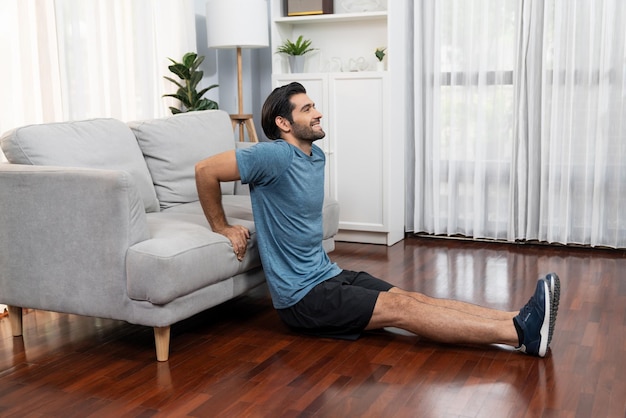 Athletic body and active sporty man using furniture for effective targeting muscle gain exercise at gaiety home exercise as concept of healthy fit body home workout lifestyle