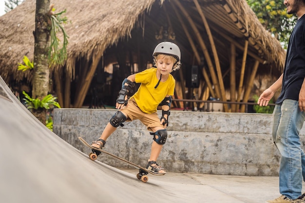 Athletic boy learns to skateboard with a trainer in a skate park Children education sports