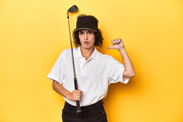 Photo athletic caucasian woman with curly hair golfing in studio feels proud and self confident