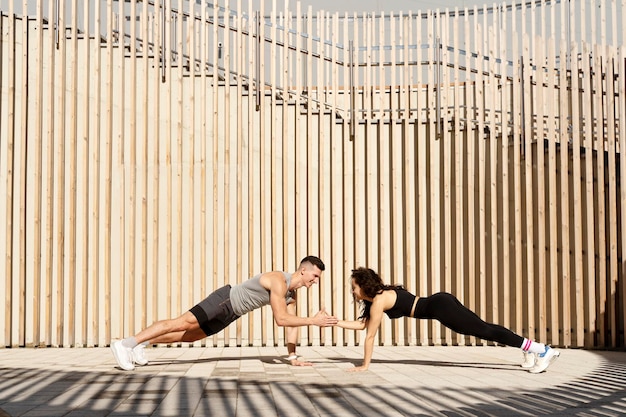 Athletic couple doing fitness exercise on city street