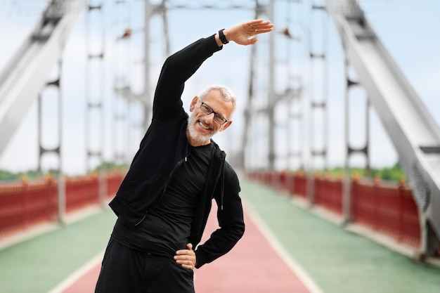 Athletic elderly sportsman stretching body while exercising outdoor