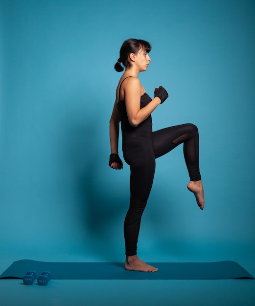 Athletic fit woman in sportwear in studio streching leg muscles during fitness workout. Personal trainer working at healthy lifestyle practicing aerobics exercices. Sport concept