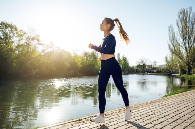 Athletic fit young woman jogging early in the morning in park