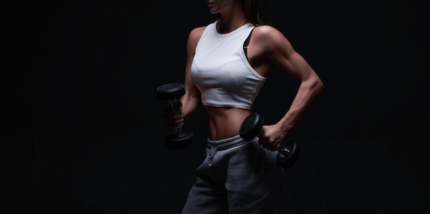 Athletic fitness woman posing in the studio on a dark background Photo of an attractive woman in fashionable sportswear Sports and healthy lifestyle