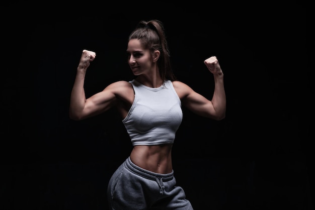 Athletic fitness woman posing in the studio on a dark background Photo of an attractive woman in fashionable sportswear Sports and healthy lifestyle