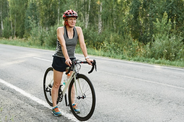 Athletic girl in helmet riding a sport bike on the road in the countryside